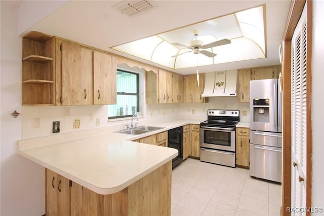 kitchen with stainless steel appliances, a peninsula, a sink, light countertops, and wall chimney exhaust hood