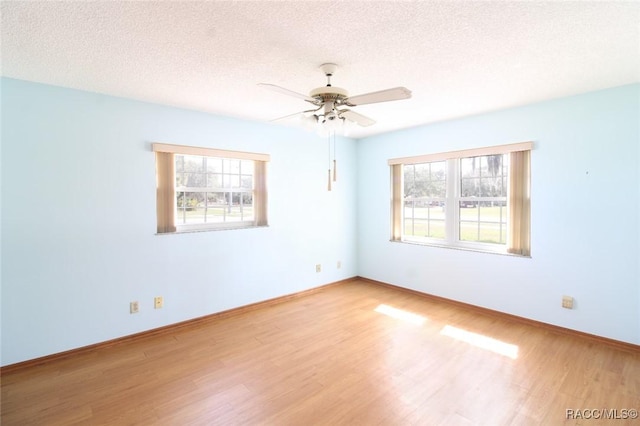 empty room featuring a ceiling fan, baseboards, a textured ceiling, and light wood finished floors