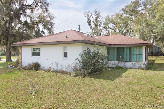 rear view of house with a lawn and stucco siding