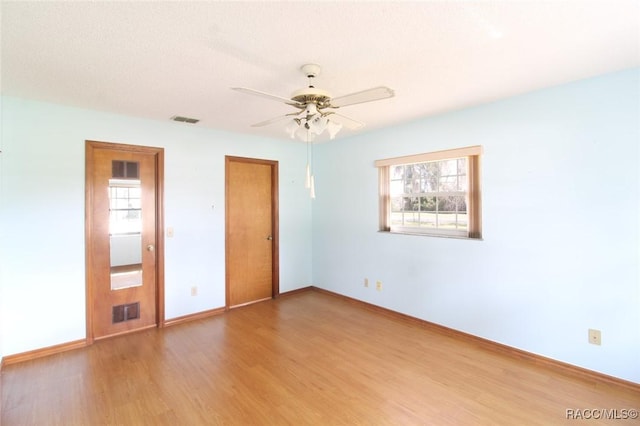 spare room with a wealth of natural light, visible vents, baseboards, and wood finished floors