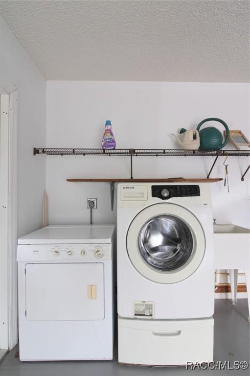 laundry room featuring laundry area, a textured ceiling, and washing machine and clothes dryer