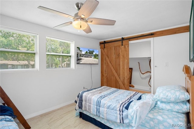 bedroom featuring ceiling fan and a barn door