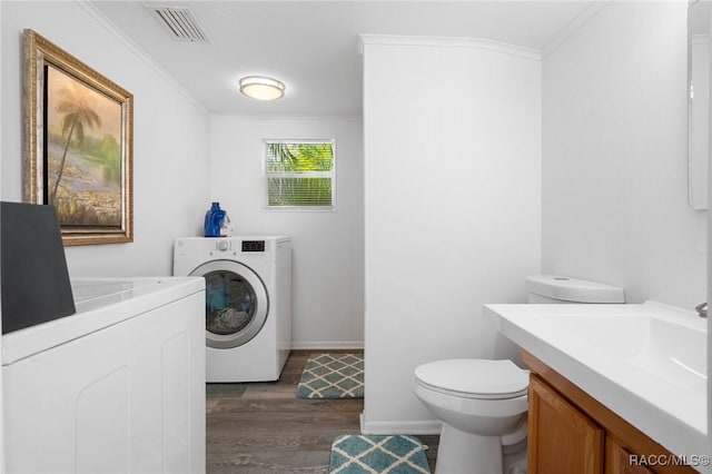 laundry room with washing machine and clothes dryer, dark hardwood / wood-style floors, and ornamental molding