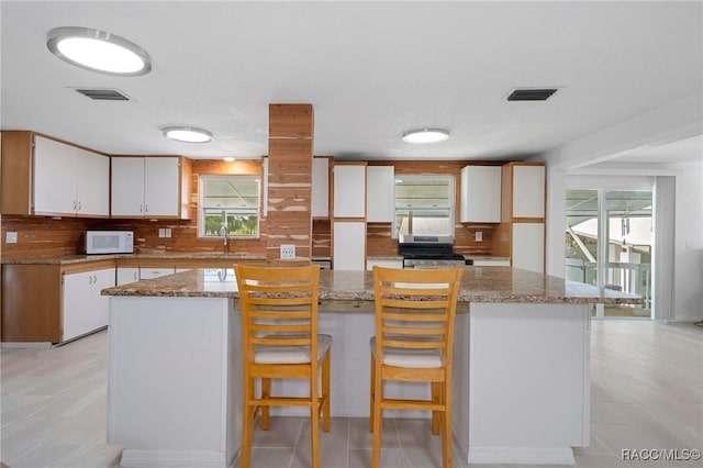 kitchen featuring backsplash, a center island, white cabinets, and plenty of natural light