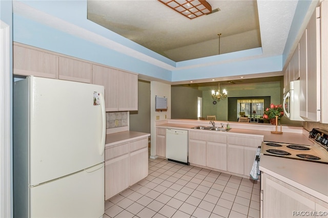 kitchen featuring sink, a raised ceiling, a notable chandelier, white appliances, and light tile patterned flooring