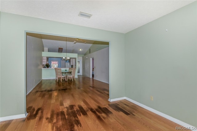 interior space with hardwood / wood-style flooring, ceiling fan with notable chandelier, lofted ceiling, and a textured ceiling