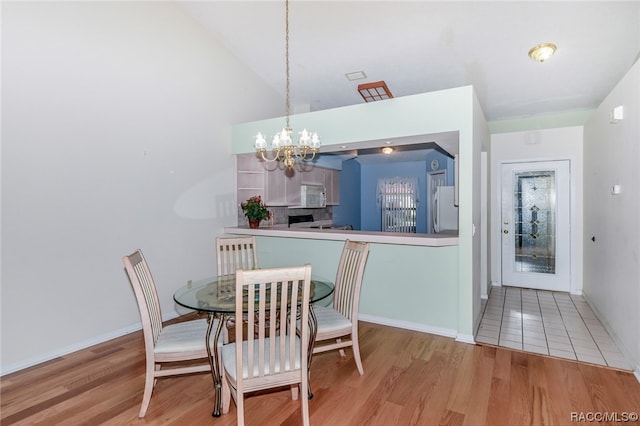 dining area featuring vaulted ceiling, light wood-type flooring, and an inviting chandelier