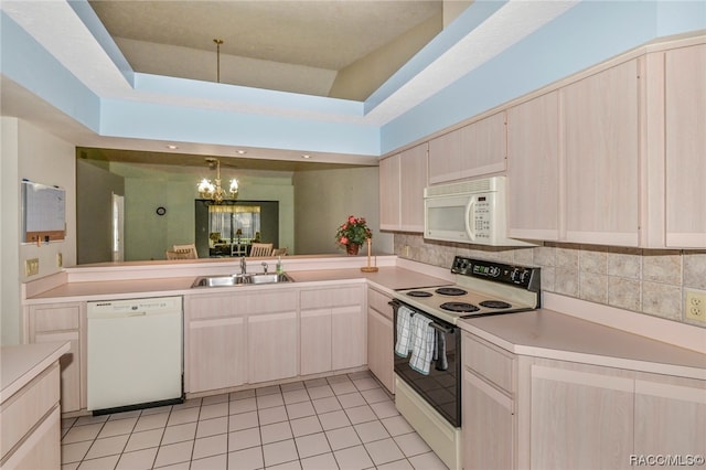 kitchen featuring white appliances, decorative backsplash, light tile patterned floors, a tray ceiling, and a notable chandelier