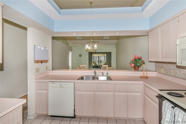 kitchen with sink, a notable chandelier, white appliances, a tray ceiling, and light tile patterned floors