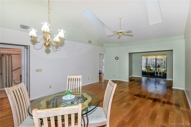 dining area featuring wood-type flooring, ceiling fan with notable chandelier, a skylight, and high vaulted ceiling