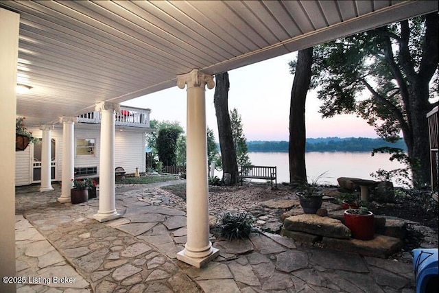 patio terrace at dusk featuring a water view