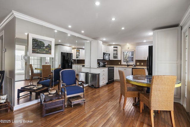 kitchen with crown molding, black appliances, backsplash, hardwood / wood-style floors, and white cabinets