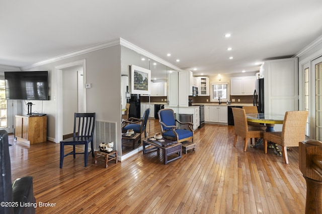 living room featuring crown molding, sink, and light hardwood / wood-style flooring