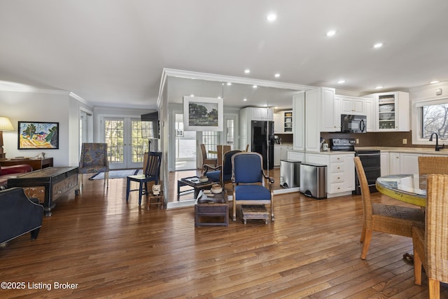 living room featuring hardwood / wood-style flooring, ornamental molding, and sink