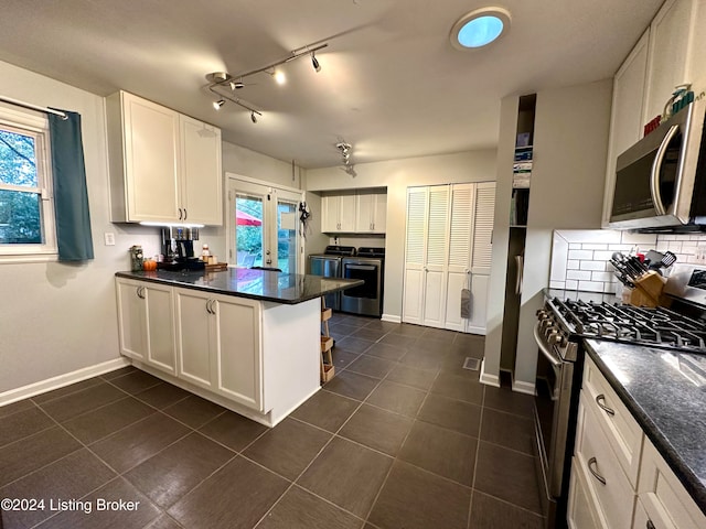 kitchen with appliances with stainless steel finishes, white cabinetry, backsplash, washing machine and clothes dryer, and kitchen peninsula