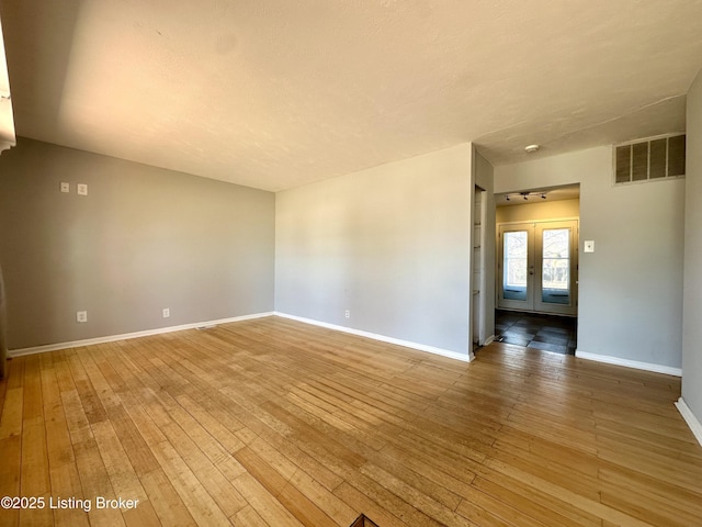 spare room with hardwood / wood-style flooring and french doors