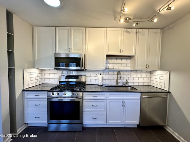 kitchen featuring sink, white cabinetry, appliances with stainless steel finishes, dark stone counters, and backsplash