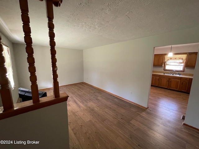 unfurnished living room with sink, a textured ceiling, and hardwood / wood-style flooring