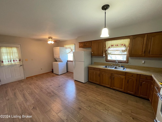 kitchen featuring ceiling fan, light wood-type flooring, pendant lighting, white fridge, and sink