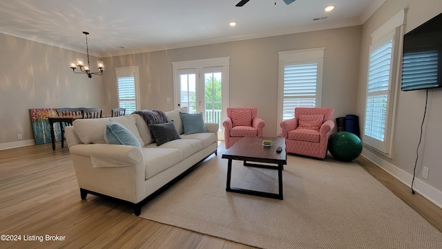 living room with crown molding, light hardwood / wood-style flooring, and ceiling fan with notable chandelier