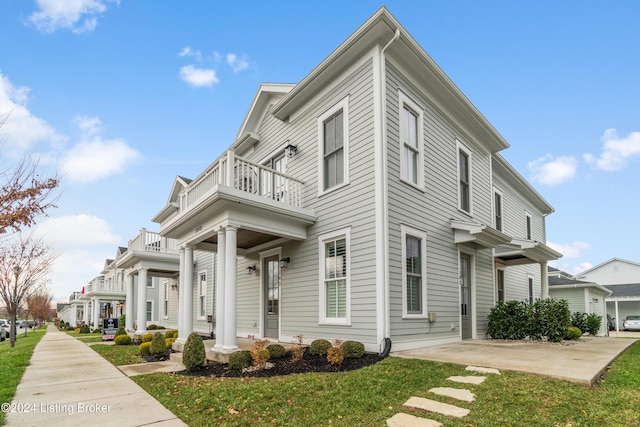 view of front of property with covered porch, a balcony, and a front yard