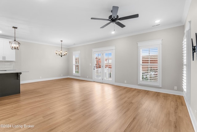 unfurnished living room with ceiling fan with notable chandelier, light hardwood / wood-style floors, and ornamental molding