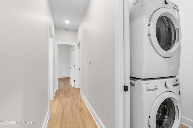 laundry area featuring stacked washer and dryer and light hardwood / wood-style flooring