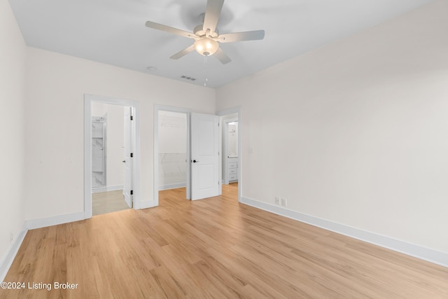 unfurnished bedroom with ensuite bath, a spacious closet, ceiling fan, light hardwood / wood-style floors, and a closet