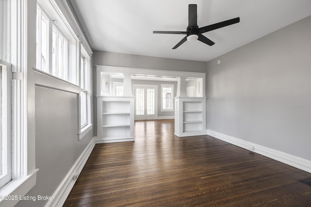 unfurnished living room featuring a ceiling fan, decorative columns, baseboards, and wood finished floors