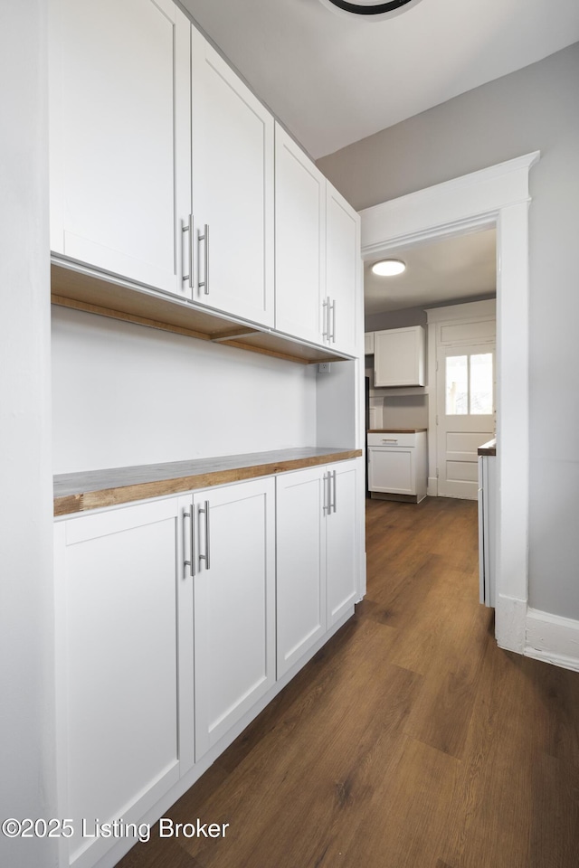 kitchen with dark wood-style floors, wood counters, white cabinetry, and baseboards