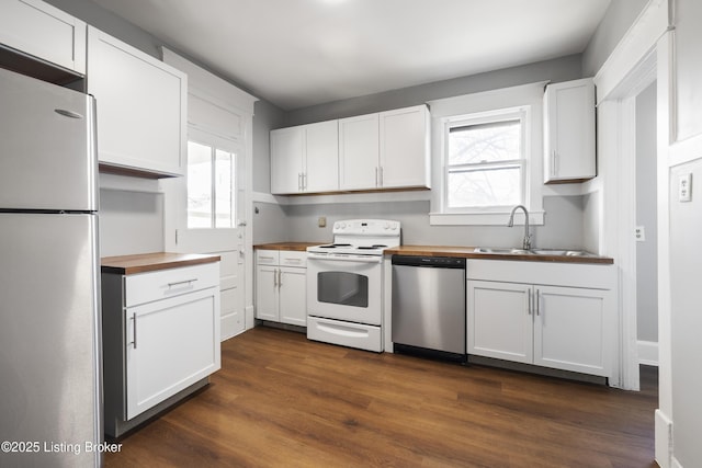 kitchen with butcher block counters, appliances with stainless steel finishes, white cabinets, and a sink