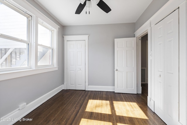 unfurnished bedroom with ceiling fan, dark wood-type flooring, and baseboards