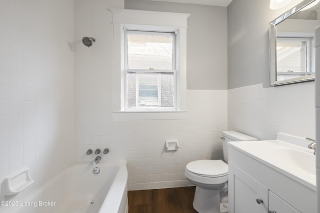 full bath with a tub to relax in, toilet, wood finished floors, vanity, and tile walls