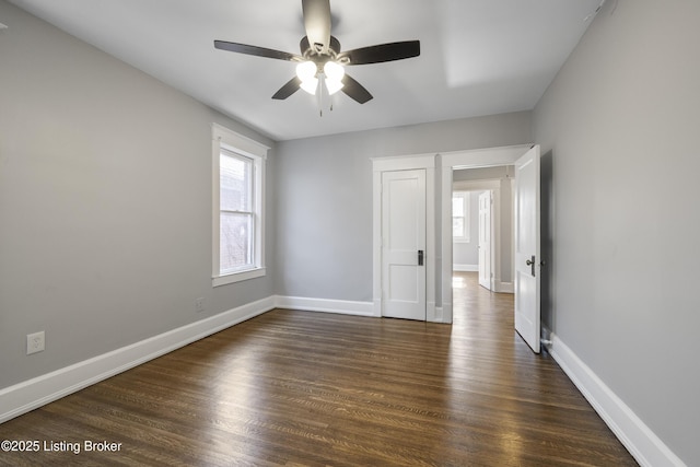 spare room featuring a ceiling fan, baseboards, and dark wood-type flooring