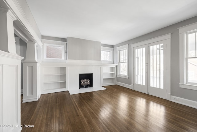 unfurnished living room with french doors, a fireplace, wood finished floors, and baseboards