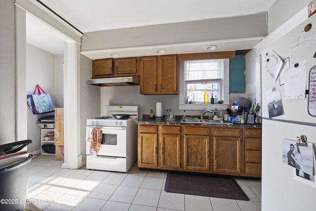 kitchen with white appliances, brown cabinets, a sink, and under cabinet range hood