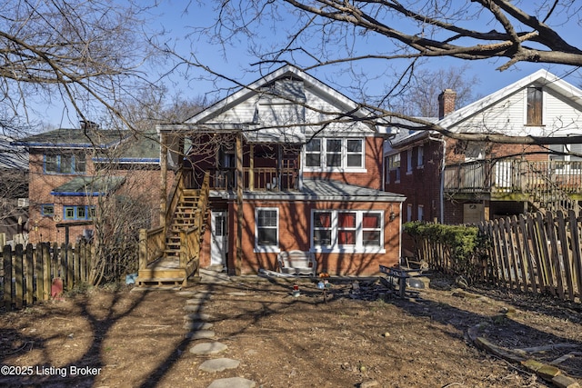 rear view of property with brick siding, fence, a chimney, and stairs