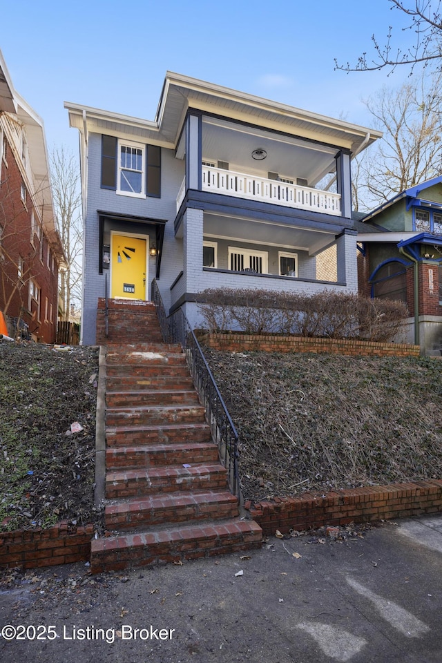 view of front of home with a balcony and brick siding