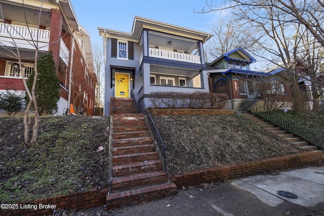 view of front of home featuring brick siding and a balcony