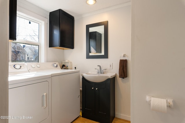 628 Harrison Ave, Louisville, KY 40217 - laundry room featuring independent washer and dryer, cabinet space, light wood-type flooring, ornamental molding, and baseboards