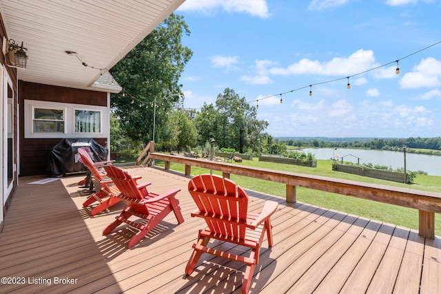 wooden deck featuring a lawn, a water view, and area for grilling