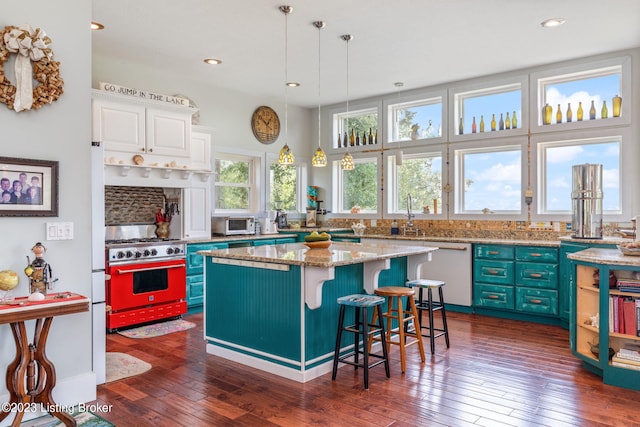 kitchen featuring a kitchen island, hanging light fixtures, dishwasher, double oven range, and white cabinetry