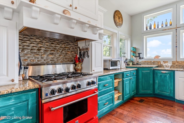 kitchen with white cabinets, gas stove, dark wood-type flooring, and light stone countertops