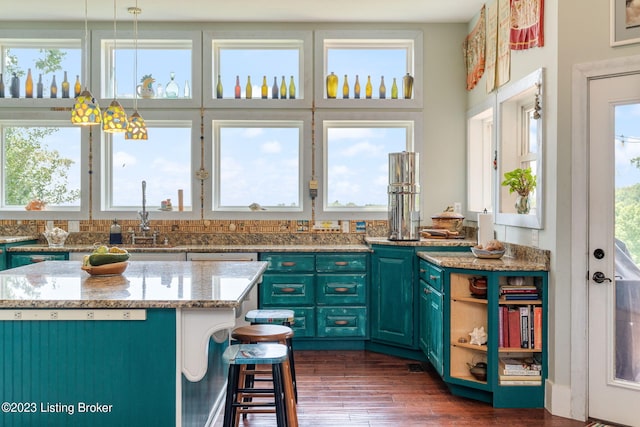 kitchen featuring light stone countertops, a kitchen island, a wealth of natural light, and dark hardwood / wood-style flooring