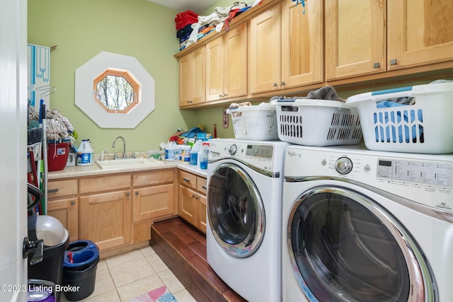 laundry area with cabinets, light tile floors, washing machine and clothes dryer, and sink