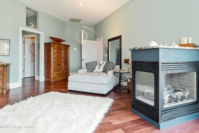 sitting room featuring dark wood-type flooring and a multi sided fireplace