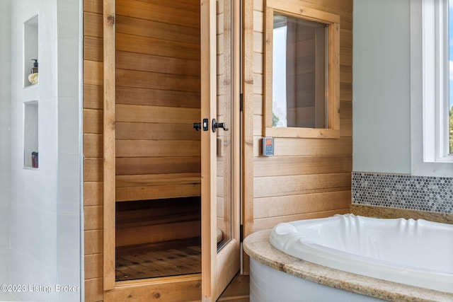 bathroom featuring wooden walls and a bathtub