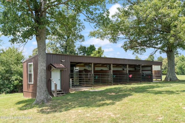 view of horse barn featuring a lawn and an outdoor structure