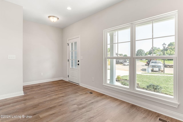 foyer featuring visible vents, baseboards, and wood finished floors