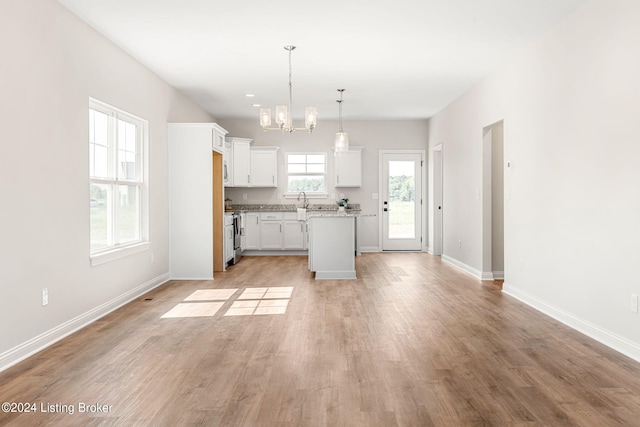 kitchen with decorative light fixtures, light wood-style flooring, white cabinets, a kitchen island, and baseboards